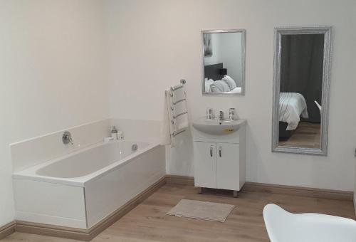 a bathroom with a tub and a sink and a mirror at Casa Mo Boutique Guest House in Bloemfontein
