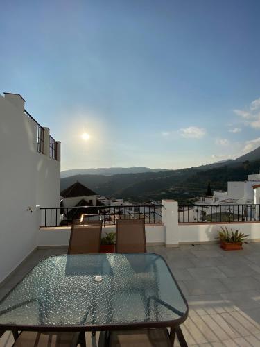 patio ze szklanym stołem i krzesłami na balkonie w obiekcie Casa con vistas 2 w mieście Frigiliana
