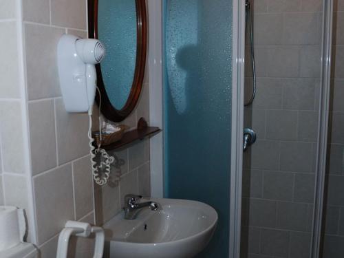 uma casa de banho com um lavatório e um chuveiro com um espelho. em Hotel Ristorante Sassi Rossi em Taceno