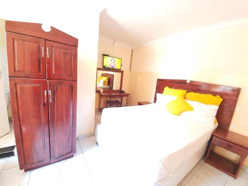 a bedroom with a bed and a wooden cabinet at The Palace Guest House in Harare