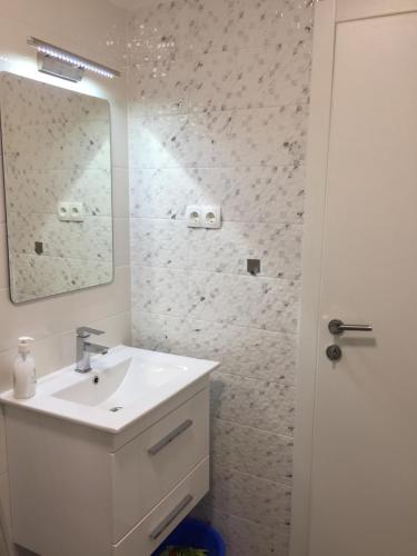 W białej łazience znajduje się umywalka i lustro. w obiekcie Memories New Studio 200 m from beach w mieście Pirovac