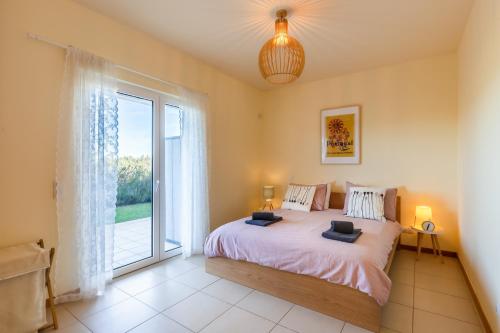 a bedroom with a bed and a large window at Casa Laranja, Aromas Burgau in Burgau