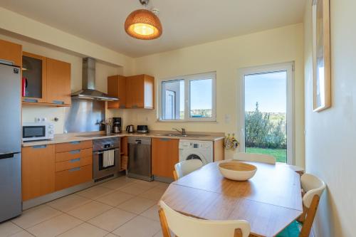 a kitchen with a wooden table and a dining room at Casa Laranja, Aromas Burgau in Burgau