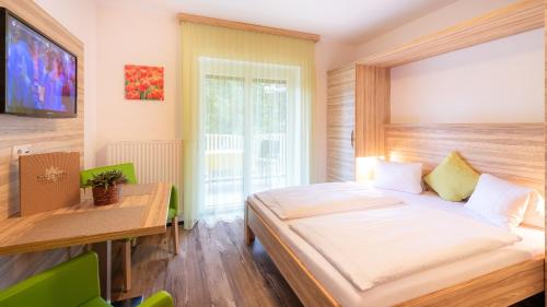 1 dormitorio con cama, escritorio y ventana en Apartments Kristan, en Sankt Kanzian