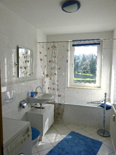 La salle de bains blanche est pourvue d'un lavabo, d'une baignoire et d'une fenêtre. dans l'établissement Ferienwohnung Lehmann, à Lunzenau