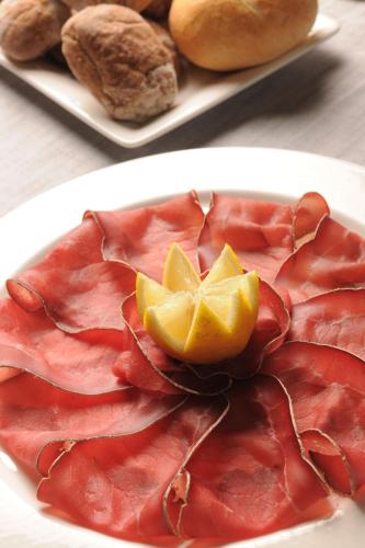 a plate of food with ham and lemons on it at Hotel Astra in Livigno
