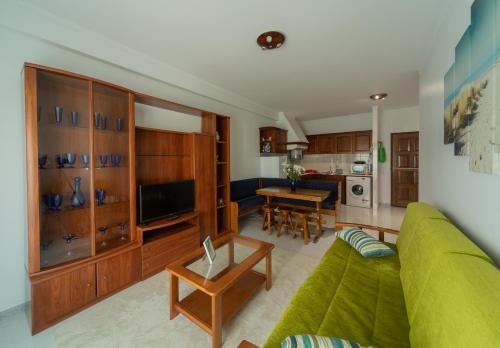 White Beach House في برايا دا أريا برانكا: غرفة معيشة مع أريكة خضراء وطاولة