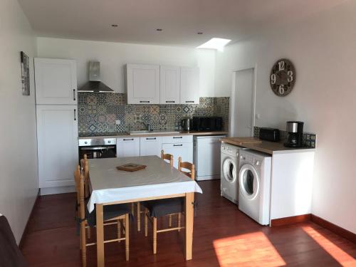 une cuisine avec une table et une machine à laver dans l'établissement Gîtes tout confort Saujon, à Saujon