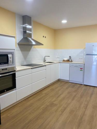 eine große Küche mit weißen Schränken und Geräten in der Unterkunft Tu&Mi Villafranca in Villafranca del Bierzo