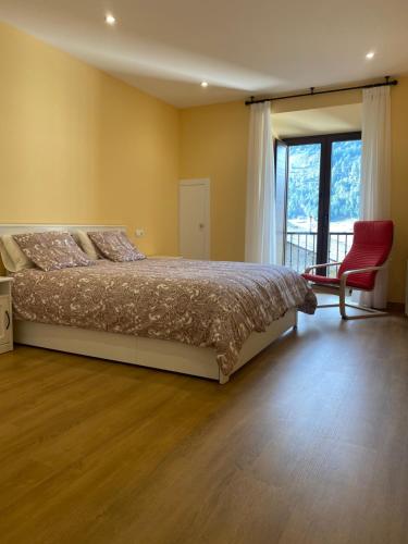 a bedroom with a bed and a chair and a window at Tu&Mi Villafranca in Villafranca del Bierzo