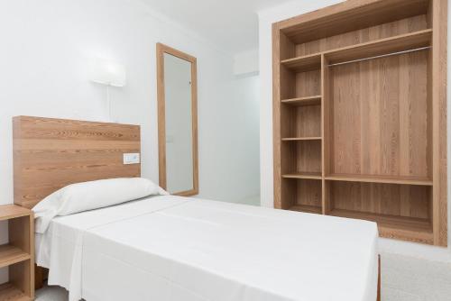 una camera con letto bianco e scaffali in legno di Cozy&Bright Double Room in Cala Ratjada a Capdepera
