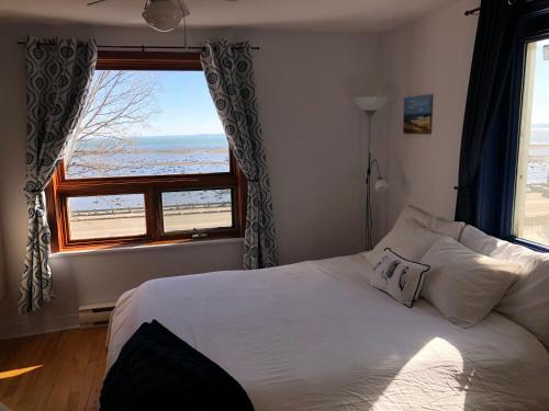 a bedroom with a bed with a view of the ocean at Les Pinsons des Rives in La Malbaie