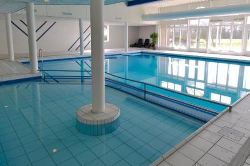 a large swimming pool in a large building at TIME-OUT met ZONNIG TERRAS, eigen KEUKEN, Dichtbij Dorp, Duinen, Strand en Vuurtoren , Incl verwarmd Hotel-ZWEMBAD in Hollum