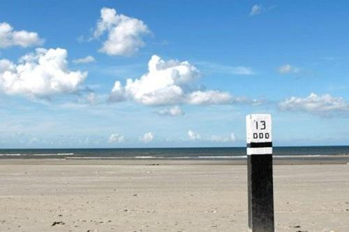 a speed limit sign on a beach with the ocean at TIME-OUT met ZONNIG TERRAS, eigen KEUKEN, Dichtbij Dorp, Duinen, Strand en Vuurtoren , Incl verwarmd Hotel-ZWEMBAD in Hollum