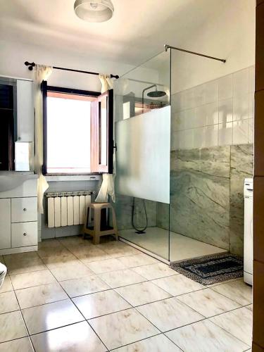 a bathroom with a glass shower and a window at Casa La Vigna in Puntalazzo