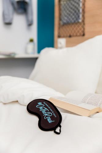 a black sign on a bed next to a book at hotelF1 Avignon Nord in Sorgues