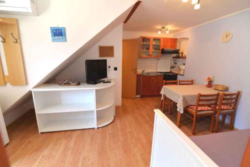 a kitchen and a dining room with a table with a television at Apartment in Veli Losinj 15050 in Veli Lošinj