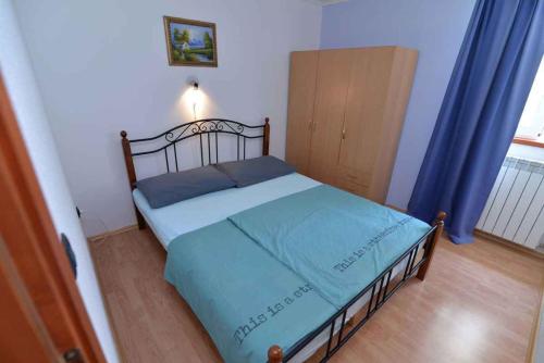 a small bedroom with a bed with a blue blanket at Apartment in Veli Losinj 15050 in Veli Lošinj