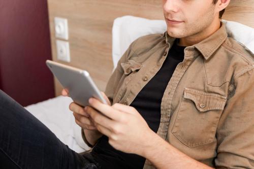 a man sitting on a chair using a tablet computer at hotelF1 Avignon Nord in Sorgues