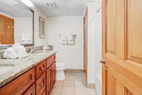 Un baño con inodoro, lavabo y espejo. en Beach Cove Bungalow, en Myrtle Beach