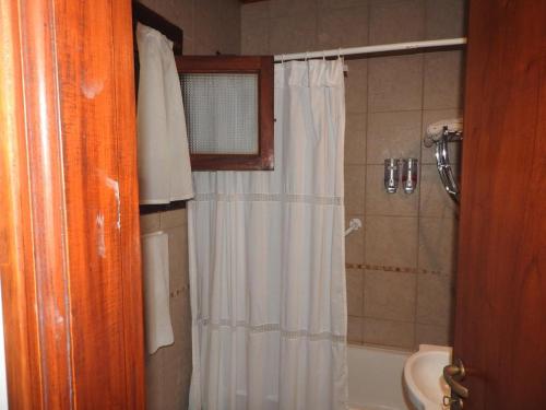 baño con ducha con cortina blanca en Hotel Las Piedras en Mar de las Pampas