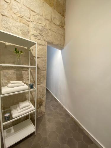 a bathroom with white shelves and a stone wall at Casa Maria in Siracusa