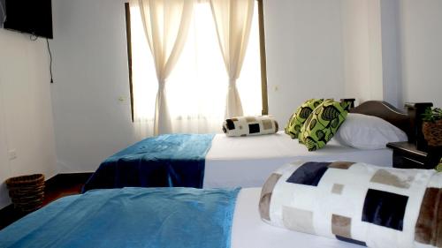 two beds in a room with a window at Hotel El Jerarca in Filandia