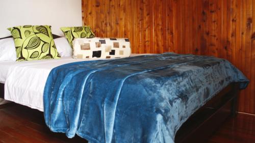 a bed with a blue blanket on top of it at Hotel El Jerarca in Filandia
