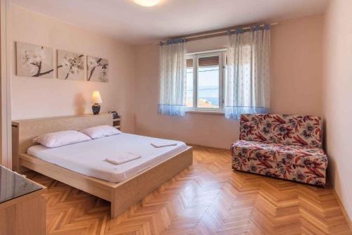 a bedroom with a bed and a chair and a window at Apartment in Vrbnik/Insel Krk 13616 in Vrbnik