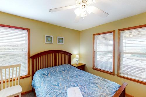 a bedroom with a bed with a ceiling fan and windows at Slow M'Ocean #7-HH in Hatteras