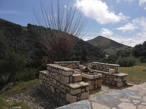 a stone fire pit in a field with a mountain at Villa Agno - Βίλα Αγνώ in Ãno KariaÃ­