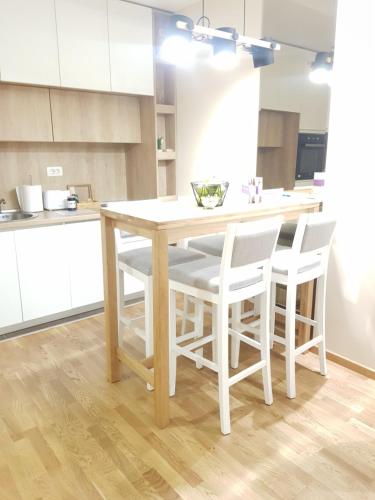 a kitchen with a wooden table and white chairs at SunStone Apartment in Zlatibor