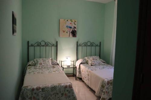 2 camas en una habitación con paredes verdes en VFT Doña Elvira, en Arjonilla