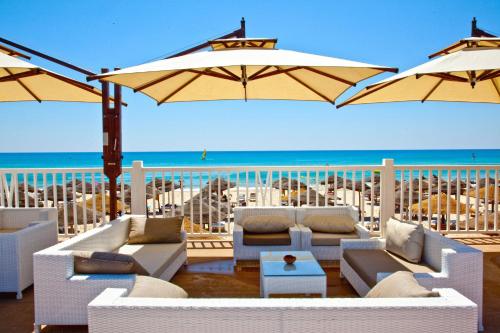 a patio with white couches and umbrellas on the beach at Samira Club Family and couples only in Hammamet