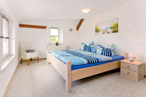 Schlafzimmer mit einem Bett mit blauer Bettwäsche und einem Fenster in der Unterkunft Holiday Home Groß Kordshagen in Arbshagen