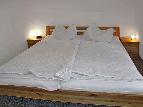 uma cama grande com lençóis brancos e almofadas em Holiday home in Zinnowitz (Seebad) 33031 em Zinnowitz