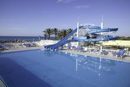 a pool with a slide in front of the ocean at Samira Club Family and couples only in Hammamet