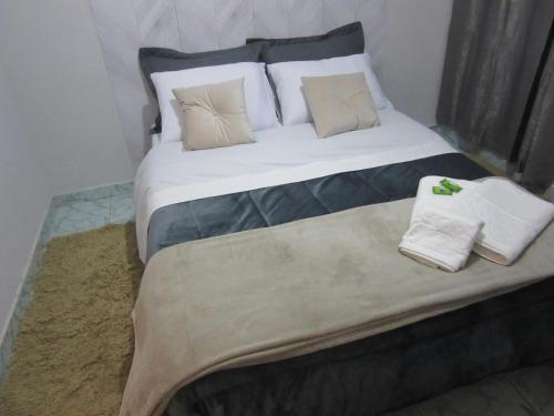 a large bed with pillows and towels on it at Kitnet Recanto de Campos-Pertinho do Centro in Campos do Jordão