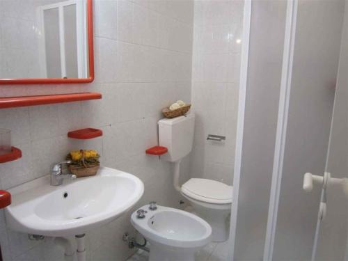 a white bathroom with a toilet and a sink at Apartments in Bibione 24581 in Bibione