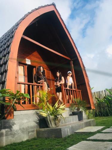 three women standing on the balcony of a small house at Volcano Valley in Kintamani