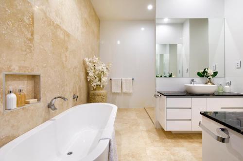 a white bathroom with a tub and a sink at Exquisite Riverside Living, Noosaville in Noosaville