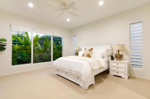 a white bedroom with a white bed and a window at Exquisite Riverside Living, Noosaville in Noosaville