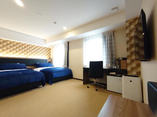 um quarto com 2 camas, uma secretária e uma televisão em Green Rich Hotel Yonago Ekimae (Artificial hot spring Futamata Yunohana) em Yonago