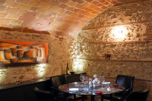 a dining room with two tables and a brick wall at Auberge Du Roua in Argelès-sur-Mer