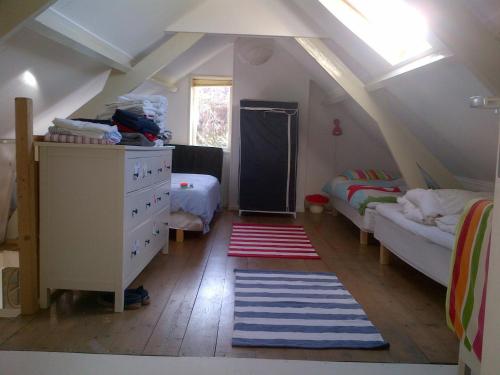 a attic room with a bed and a dresser and a bedroom at Authentic Farmhouse, near beach in Kloosterzande