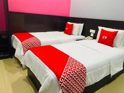 two beds in a hotel room with red and white sheets at Ct Hotel in Sitiawan