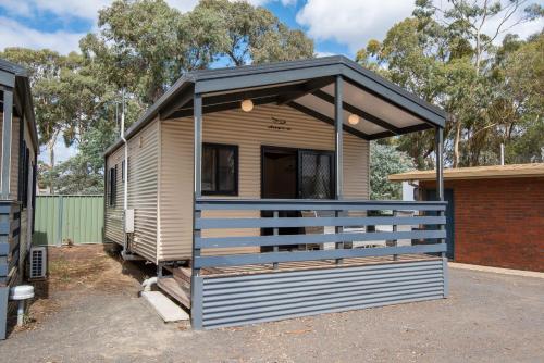 a tiny house with awning in a parking lot at Golden Country Motel and Caravan Park in Maryborough