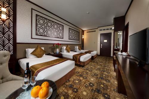a hotel room with two beds and a television at Mithrin Hotel Halong in Ha Long