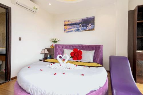 a bedroom with a purple bed with a red flower on it at Hoang Trinh Hotel in Hoi An