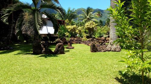 a garden with rocks and palm trees and a house at Eco Lodge Village Temanoha in Paopao